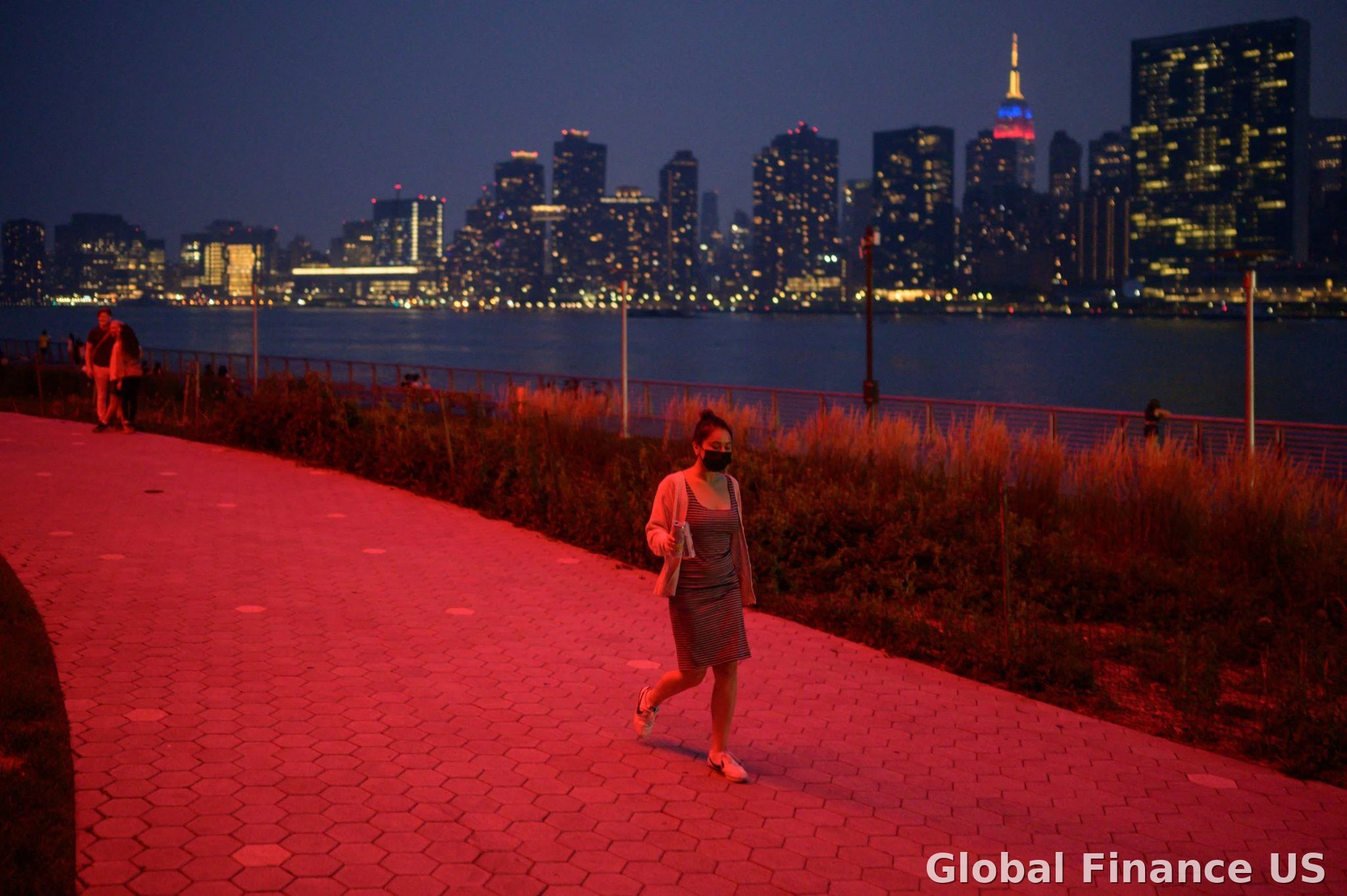 Woman wearing a mask walking in a polluted urban city at night with red air quality glow, highlighting how to Protect Your Family from Pollution in the USA 2026